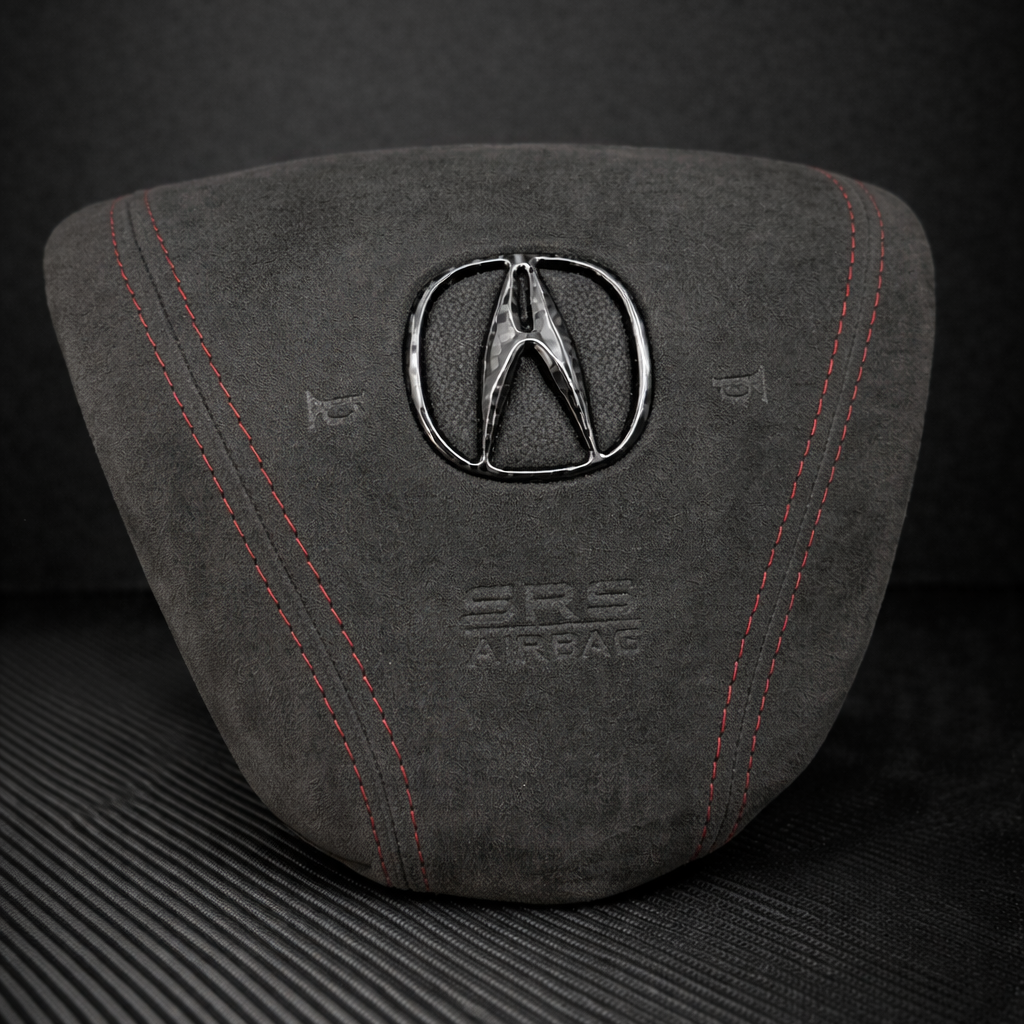Gray airbag cover with Acura logo on a dark background